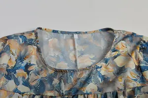 Detaillierte Nahaufnahme des Rundhalsausschnitts eines Kleides mit Aquarell-Blumenmuster