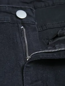 Close-up detail of black denim jeans featuring metal zipper and silver button fastener