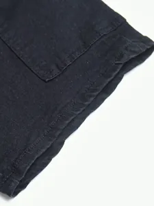 Detail shot of black denim jeans showing high-quality stitching and fabric texture