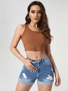 Dettaglio di shorts in denim blu a vita alta con strappi artistici e orlo risvoltato alla moda.