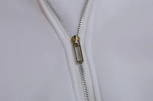 Close-up view of durable silver metal zipper on white fleece hoodie sweatshirt detail.