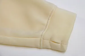 Close-up detail of cream sweatshirt sleeve with integrated thumbhole cuff