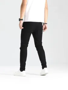 Jeans skinny neri strappati da uomo con dettagli elasticizzati, vista posteriore.