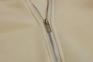 Macro detail shot showing silver metal zipper on soft cream-colored fleece hoodie fabric