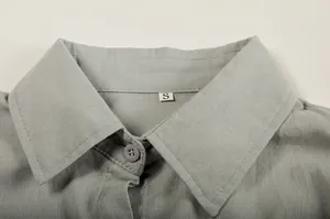 Close-up of a solid color lapel shirt collar with a visible size S tag