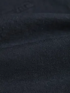 Macro detail of high-quality black denim fabric showing the weave and texture.