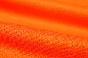 Primo piano del tessuto a maglia arancione brillante con fini dettagli sulla trama.