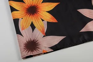 Nahaufnahme eines lebendigen Blumendrucks auf elegantem schwarzen Kleiderstoff mit Saum