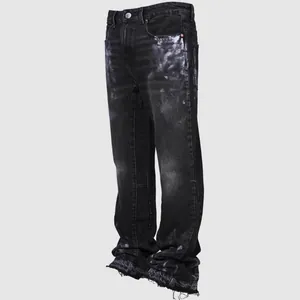 Detail view of men's distressed straight-leg jeans with paint splatters and raw hem.