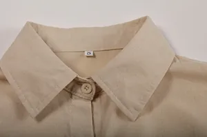Detail view of beige linen-blend shirt collar with stitching and button detail