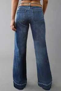 Back view of dark washed women's flared denim pants featuring a stylish frayed raw hemline