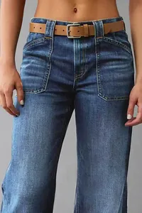 Close-up detail of women's washed blue flare jeans featuring front pockets and brown belt