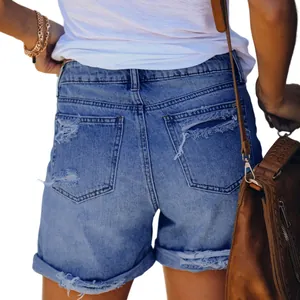Close-up of ripped denim shorts back pockets and frayed hem details on a model.
