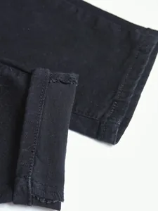 Close-up of slim fit black denim jeans showing fabric texture and hem stitching detail