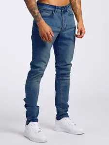 Vue détaillée du jean en denim bleu ajusté pour homme associé à des baskets blanches simples