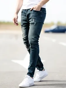 Detailed close-up view of men's slim-fit blue denim jeans featuring distressed knee accents.