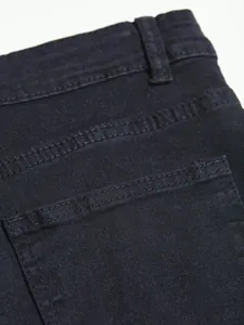 High quality close-up of men's black slim fit denim jeans back pocket and waist details