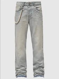 Detail of light blue straight leg jeans with pearl accents and decorative waist chain