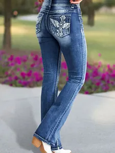 Back view of women's flared jeans featuring intricate wing and cross embroidery on pockets