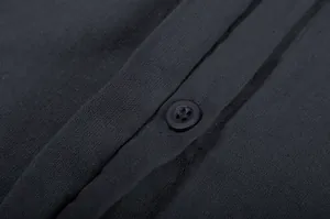 Close-up detail of dark linen fabric texture and black button on a casual shirt.