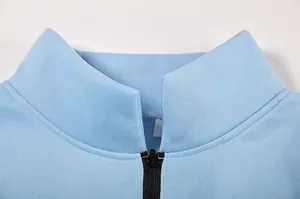 Primo piano del colletto di una felpa azzurra con dettagli della cerniera nera di qualità