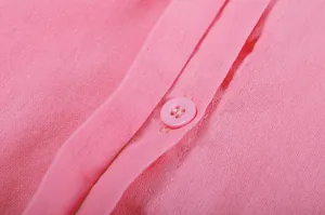 Macro view of solid pink fabric texture and matching button on casual long-sleeve shirt
