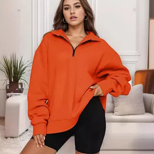 Felpa casual da donna con mezza zip arancione brillante in un ambiente interno accogliente