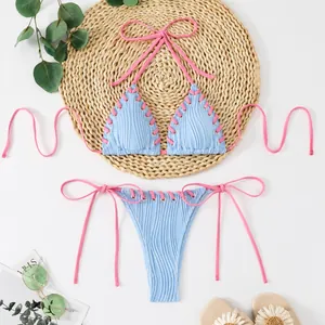 Detail view of light blue textured bikini featuring pink contrast lacing and halter ties.