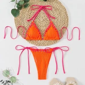 Detailed view of orange ribbed bikini with neon pink lace-up ties and eyelet accents