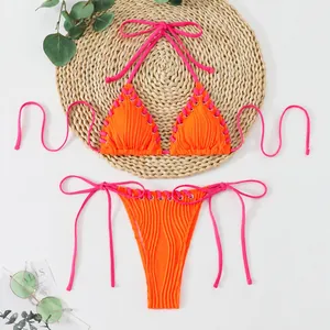 Detailed view of orange ribbed bikini with neon pink lace-up ties and eyelet accents