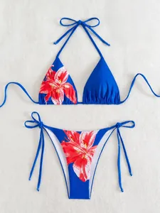 Flat lay of blue two-piece bikini set with vibrant red floral print and side ties
