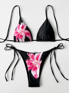 Detailansicht eines schwarzen zweiteiligen Bikinis mit lebhaftem rosa Lilien-Blumenmuster.