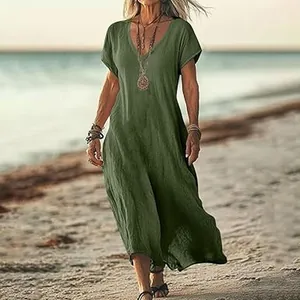 Detailed view showing the loose fit of a green V-neck cotton linen maxi dress on a beach.