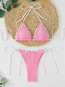 Pink halter neck bikini set with white lacing details and ribbed jacquard texture.