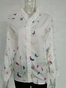 Close-up detail of elegant white long-sleeved shirt with ruffles and butterfly prints