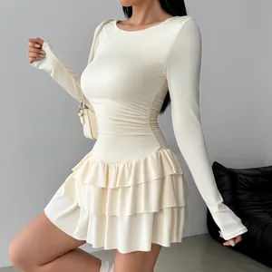 Detailed view of a white long sleeve dress featuring a ruffled hem and a slim waistline