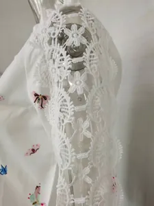Close-up of white lace floral trim and butterfly print on a women's blouse shirt
