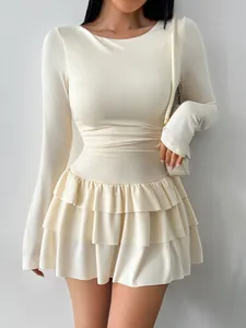 Close-up detail of a cream-colored slim-fit long-sleeve dress with a ruffled skirt