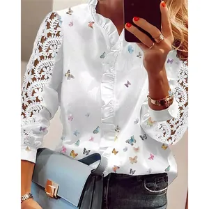Close-up detail of white blouse featuring colorful butterfly prints and elegant floral lace sleeves.