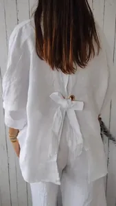 Vue détaillée du dos d'une chemise en lin blanche avec un nœud élégant et des œillets.