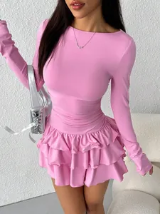 Detailed view of pink long-sleeved mini dress with layered ruffle hem and slim fit.