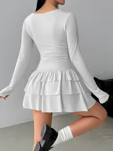 Detail of white long-sleeved slim-fit dress featuring a layered ruffled skirt design
