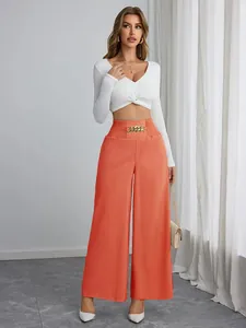 Elegante koraalkleurige wijde broek met hoge taille, gouden ketting en witte crop top