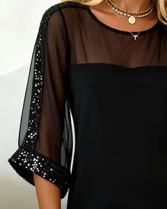 Detail of black dress featuring sheer mesh neckline and sequin embellished sleeves