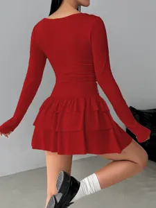 Close-up detail of red long-sleeved dress with tiered ruffled skirt and slim fit design