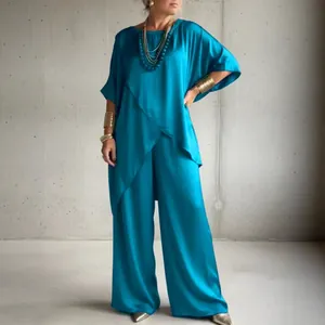 Elegant turquoise satin two-piece set with irregular hem tunic and wide-leg trousers.