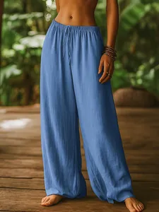 Detailed view of blue linen wide-leg pants worn by a model in a lush tropical setting