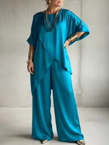 Elegant turquoise satin two-piece set with asymmetrical top and wide-leg trousers.