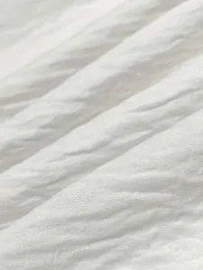 Macro detail of soft white pleated fabric texture for women's long homewear dress