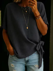 Detail of navy blue short sleeve top featuring a chic side knot hem design